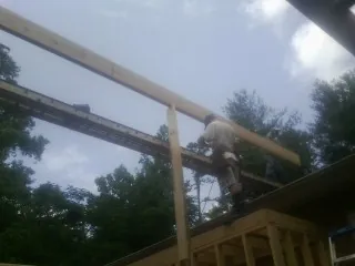 Carpenter setting a ridge beam over a new addition frame — Ice Dam Removal by Roofing Brothers in Elmo