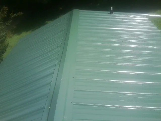 New green metal panels meeting at the ridge of a roof — Flat Roof Repair work by our crew in Elmo