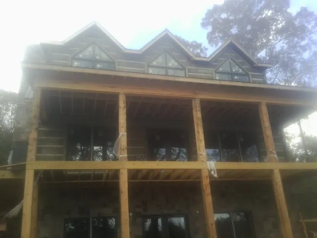 Dormers and porch framing on a large log home under construction — Roof Coating work by our crew in Elmo