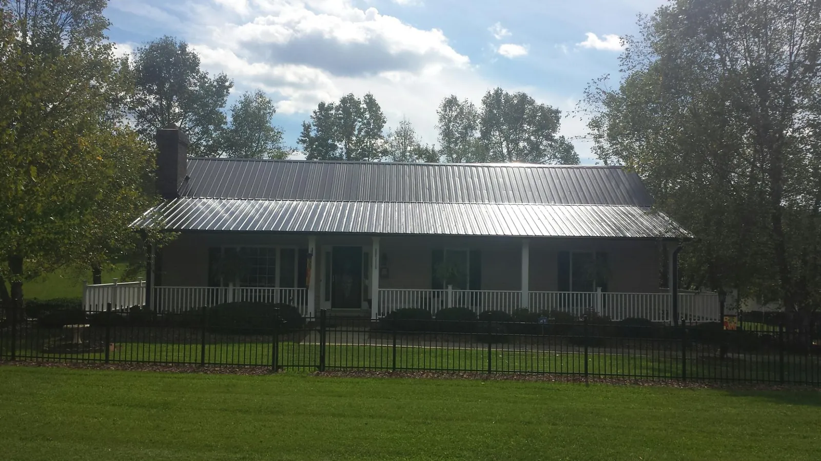 Gray metal roof on a brick ranch with a full width front porch — Gutter Guard Installation work by our crew in Elmo